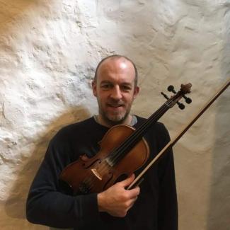 Photo of Tom Deam holding his violin